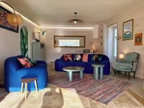 A living room with a blue sofa, a small round table, and a colorful rug. - Townhouse "La Petite Rochelaise" (La Jarne)