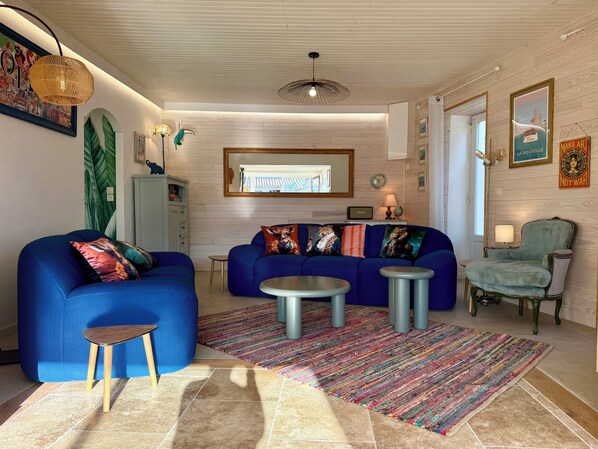 Una sala de estar con un sofá azul, una mesita redonda y un tapete colorido.