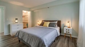 A bedroom with a bed, nightstands, a dresser, and a closet.