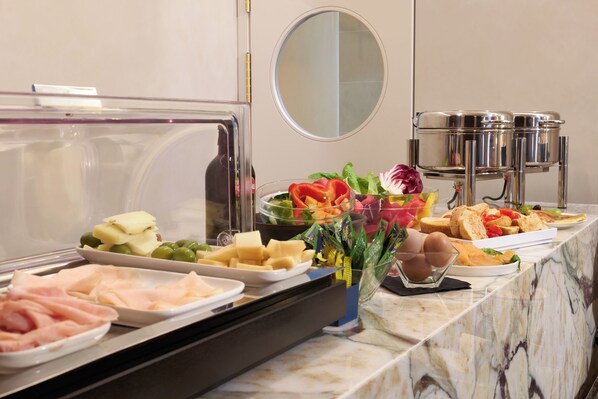 A buffet with various food items including meats, cheeses, fruits, and vegetables.