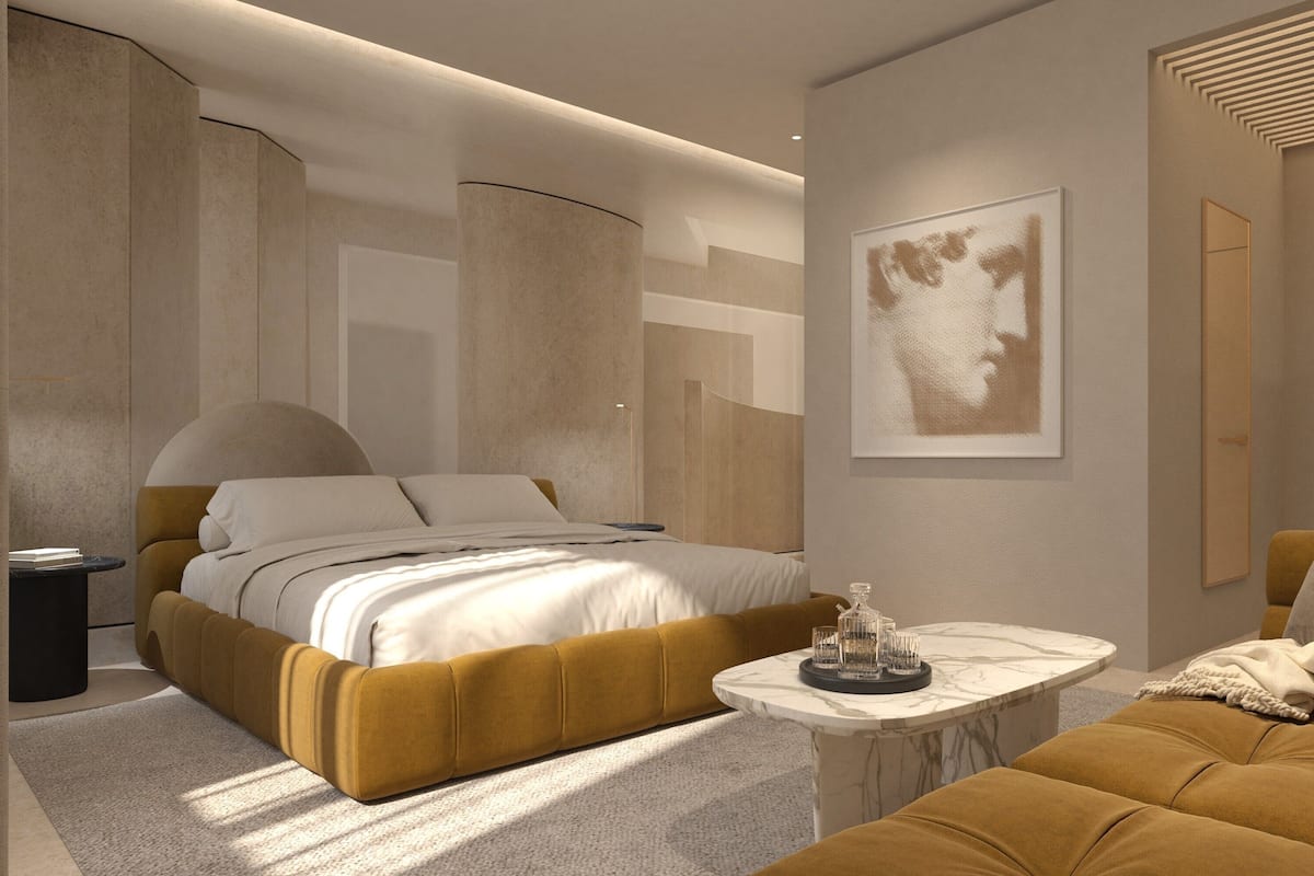 A modern bedroom with a large bed, a sofa, a small coffee table, and a wall-mounted artwork.