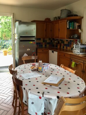 Enjoy meals in this well-equipped kitchen with a refrigerator, dining table, and ample countertop space.