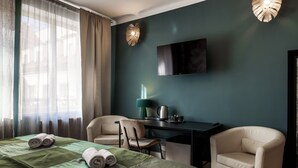 Habitación de hotel con cama, dos sillas, escritorio, televisión de pantalla plana y lámpara.