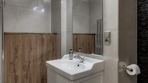 Un baño con lavamanos blanco, espejo y pared de paneles de madera.