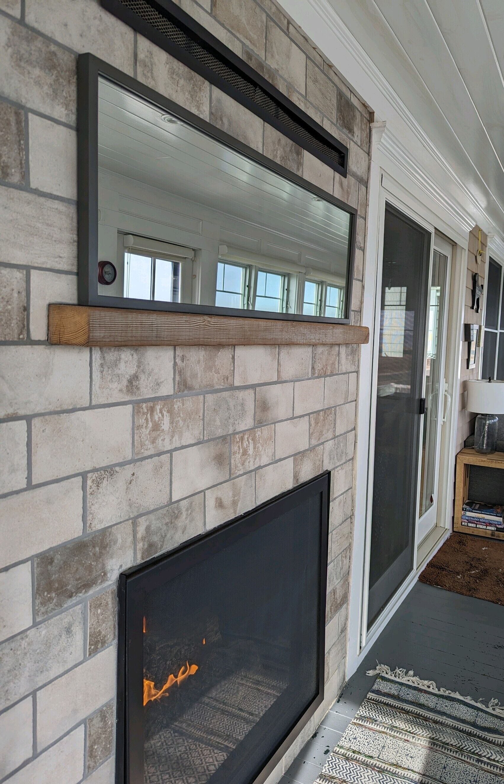 A fireplace with a stone facade, a wooden shelf above it, and a glass door to the right.