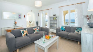 A modern living room with two grey sofas, a coffee table, and a bookshelf.