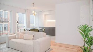 Ein modernes Wohnzimmer mit einer Couch, einem Esstisch und einer Küchenzeile.