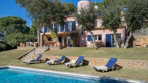 A two-story building with a swimming pool, outdoor seating, and a stone staircase leading to the entrance.