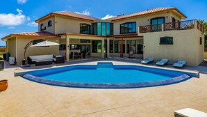 Uma casa de dois andares com piscina, área de estar ao ar livre e varanda.