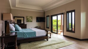 Quarto espaçoso com uma cama grande, mesa de cabeceira, televisão e vista para o exterior através de uma porta de correr.
