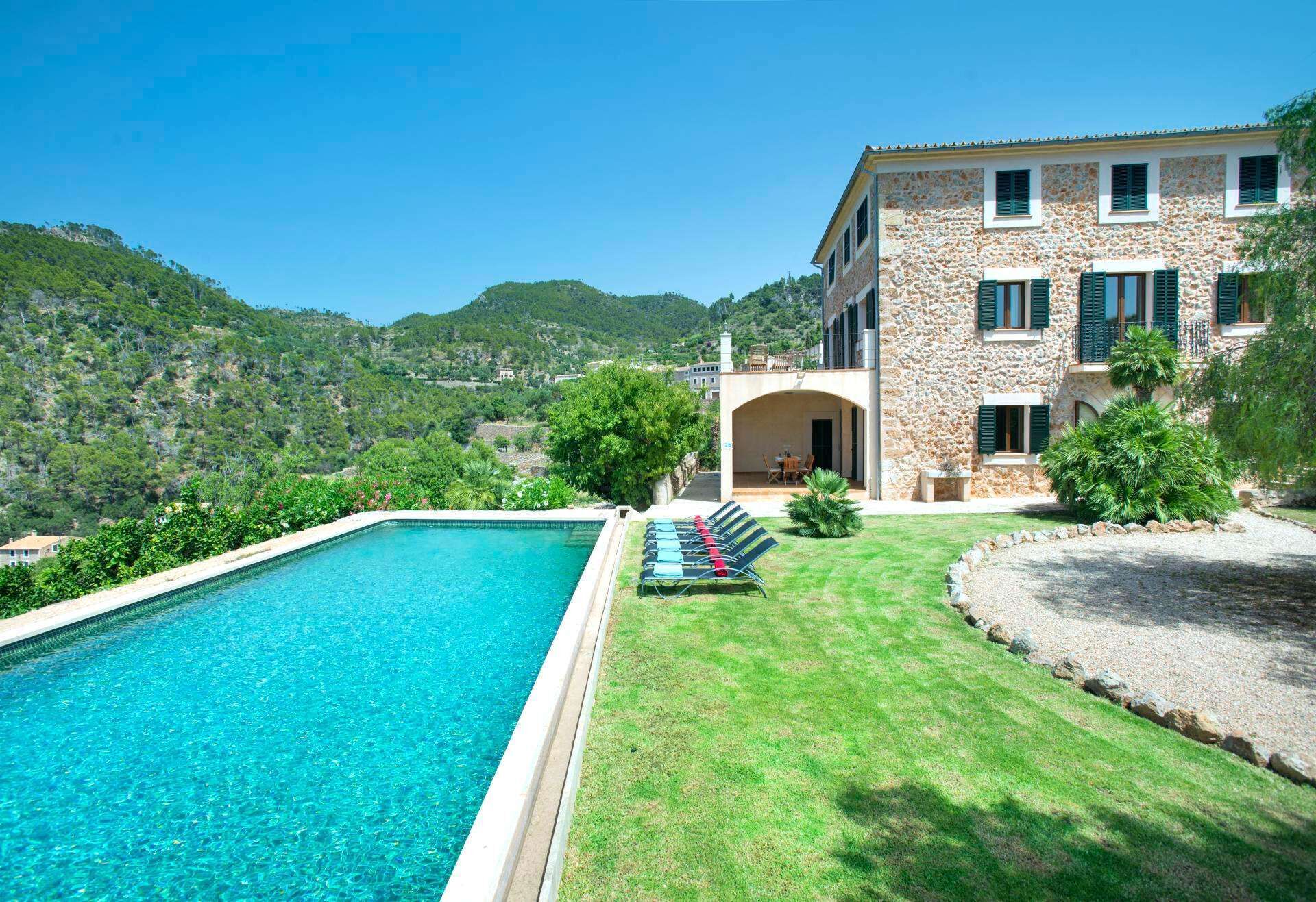A stone building with a swimming pool and a grassy lawn.