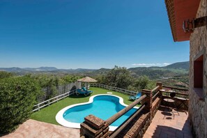 A swimming pool with a wooden deck and a view of the countryside.