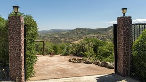 A gated entrance with a view of rolling hills and vineyards.