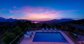 Area piscina con sedie a sdraio e vista sulle montagne al tramonto.
