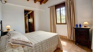 A bedroom with a bed, a dresser, a window with curtains, and a lamp on the dresser. - Casa Irene - Four Bedroom Villa, Sleeps 7 (El Gastor)