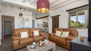 A modern living room with two brown leather sofas, a coffee table, and a large window with a view of greenery. - El Granadino - Two Bedroom Villa, Sleeps 4 (El Gastor)