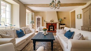 A living room with two white sofas, a black coffee table, a chandelier, and a fireplace.