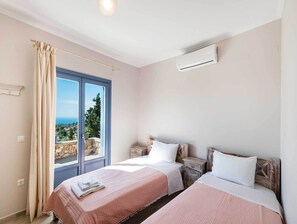 Un dormitorio con dos camas, una ventana con cortinas, un equipo de aire acondicionado y vistas al paisaje.