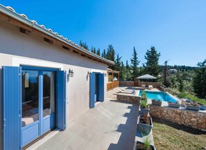 Una casa con piscina, patio y vistas a los árboles circundantes.