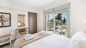 A bedroom with a bed, a desk, a chair, and a balcony with outdoor furniture. - Eratito - Three Bedroom Villa, Sleeps 6 (Tsoukalades)