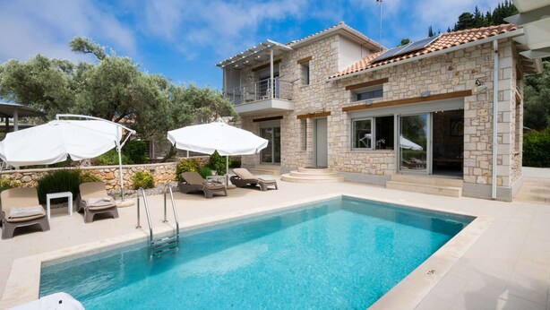 A swimming pool with lounge chairs and umbrellas, a stone building with a balcony, and a clear sky. - Eratito - Three Bedroom Villa, Sleeps 6 (Tsoukalades)