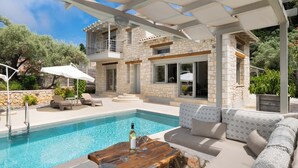 A poolside area with a stone building, outdoor seating, and a pergola. - Eratito - Three Bedroom Villa, Sleeps 6 (Tsoukalades)