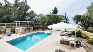 Ein Schwimmbecken mit Liegestühlen und einer überdachten Sitzgruppe.