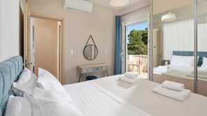 Een hotelkamer met een bed, een klein bureau, een spiegel en een balkon met buitenmeubels.