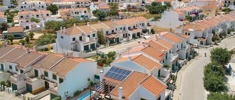 A residential area with white houses, red-tiled roofs, and a swimming pool.