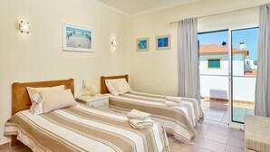 Quarto de hotel com duas camas, varanda e vista para prédios.
