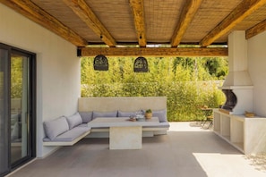 Eine Terrassenanlage im Freien mit einer eingebauten Couch, einem Tisch und einem Grill.