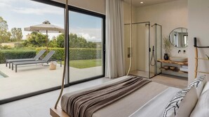 Un dormitorio con un ventanal grande, una cama, ducha y vistas al exterior.