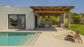 Un patio moderno al aire libre con piscina, una pérgola de madera y un área de descanso.