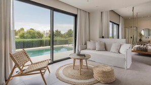 Una sala moderna con un gran ventanal que da a una piscina, un sofá, una mesa redonda y una silla.