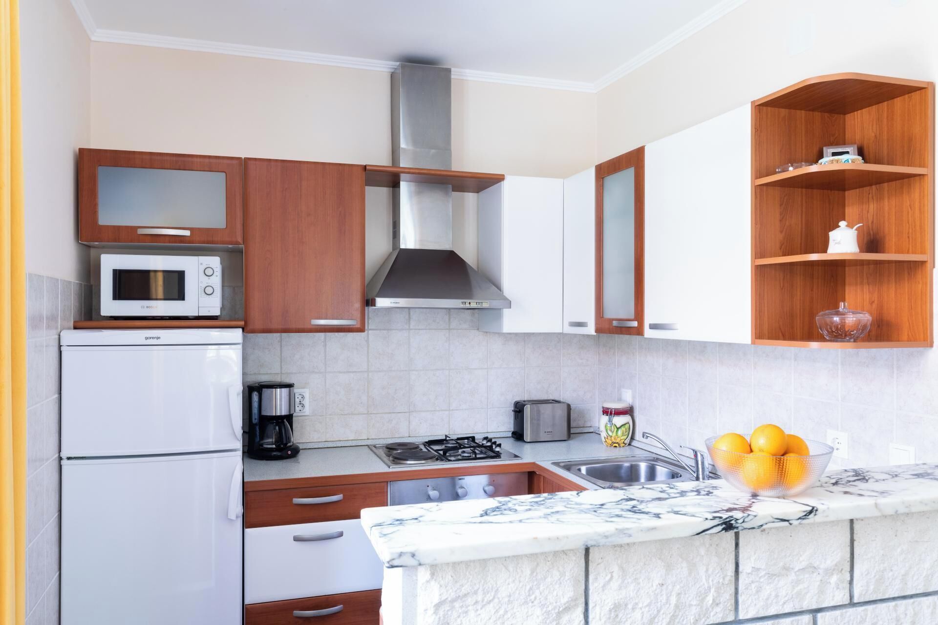 Una cocina moderna con gabinetes blancos, microondas integrado, estufa y pileta.
