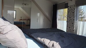 A bedroom with a bed, a wardrobe, and a window with curtains. - Relaxation oasis in the heart of Rheinhessen, Haus Weinbergsblick (Armsheim)