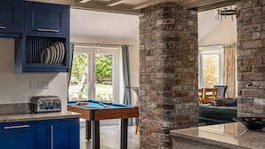 Een keuken met blauwe kasten, een pooltafel en een bakstenen muur.