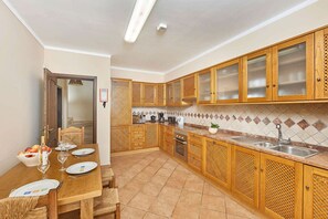 Enjoy meals in this well-equipped kitchen with oven and stainless steel sink, adjacent to a dining area with table and chairs.