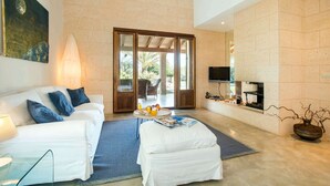 A spacious living room with a white sofa, a coffee table, and a TV mounted on the wall. - Sa Rota Nova - Three Bedroom Villa, Sleeps 6 (Mallorca)