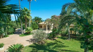 A villa surrounded by lush greenery and palm trees, with a clear blue sky. - Ca'n Jaume Barretes - Four Bedroom Villa, Sleeps 8 (Mallorca)