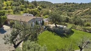 Une villa dotée d’un toit en tuiles, entourée d’une végétation luxuriante et de collines.