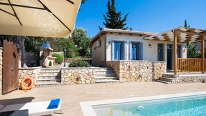 A poolside area with a stone wall, a wooden deck, and a pool.