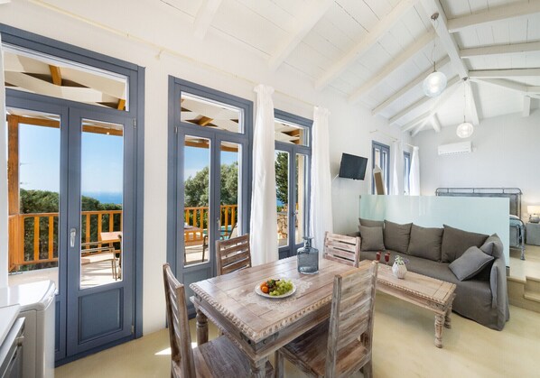 Amplia habitación con una mesa de comedor de madera, un sofá y vistas al exterior.