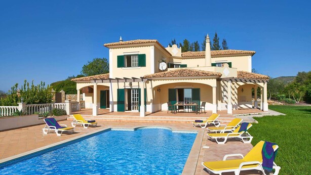 Une maison à deux étages avec une piscine, un espace salon extérieur et un jardin.