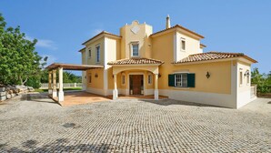Une maison à deux étages, avec un toit en tuiles, une entrée centrale et une cour dallée.