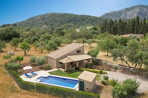 Eine Villa mit Swimmingpool, umgeben von Bäumen und einem Bergpanorama.