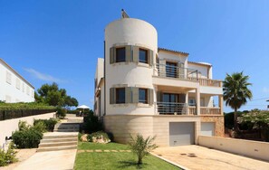 Um edifício de vários andares com uma seção central curva, varandas e uma garagem.
