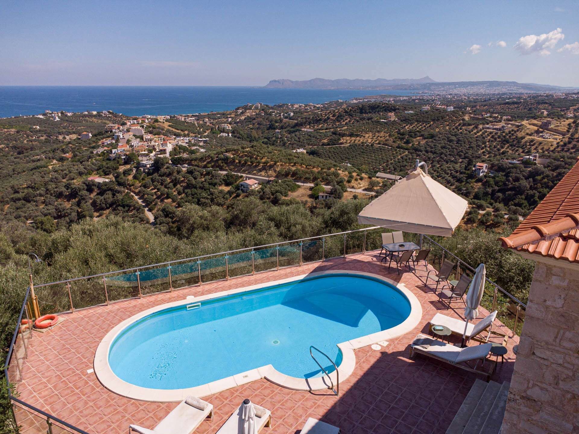 A swimming pool with a view of the sea and a hilly landscape.