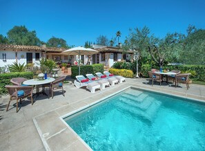 A poolside area with lounge chairs, a table, and a small pool.