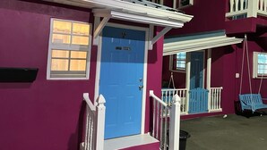 Un edificio de dos pisos con una puerta azul y barandillas blancas.